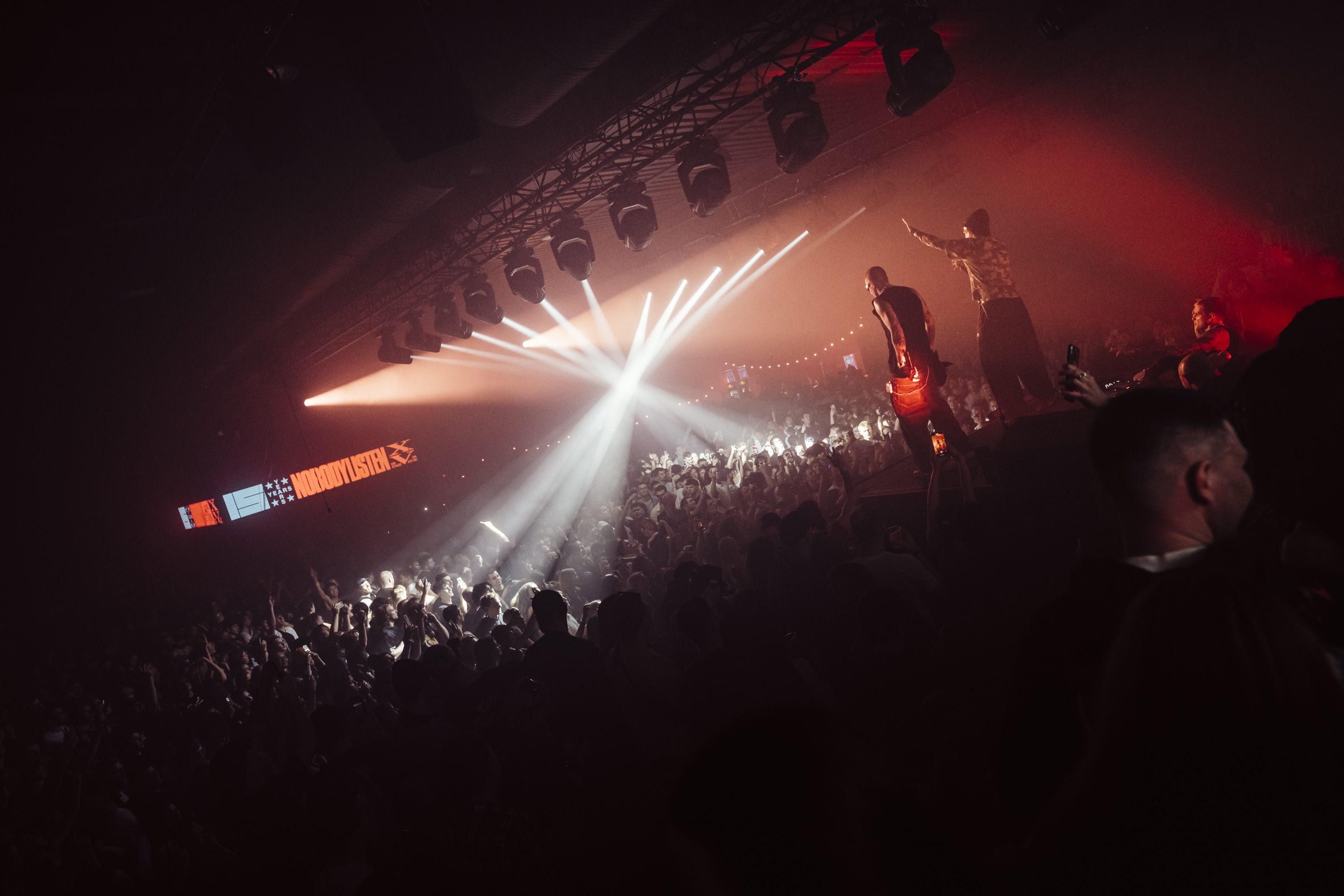 NOBODYLISTEN 15YRS — performers on stage above a dense crowd bathed in red light with the anniversary branding